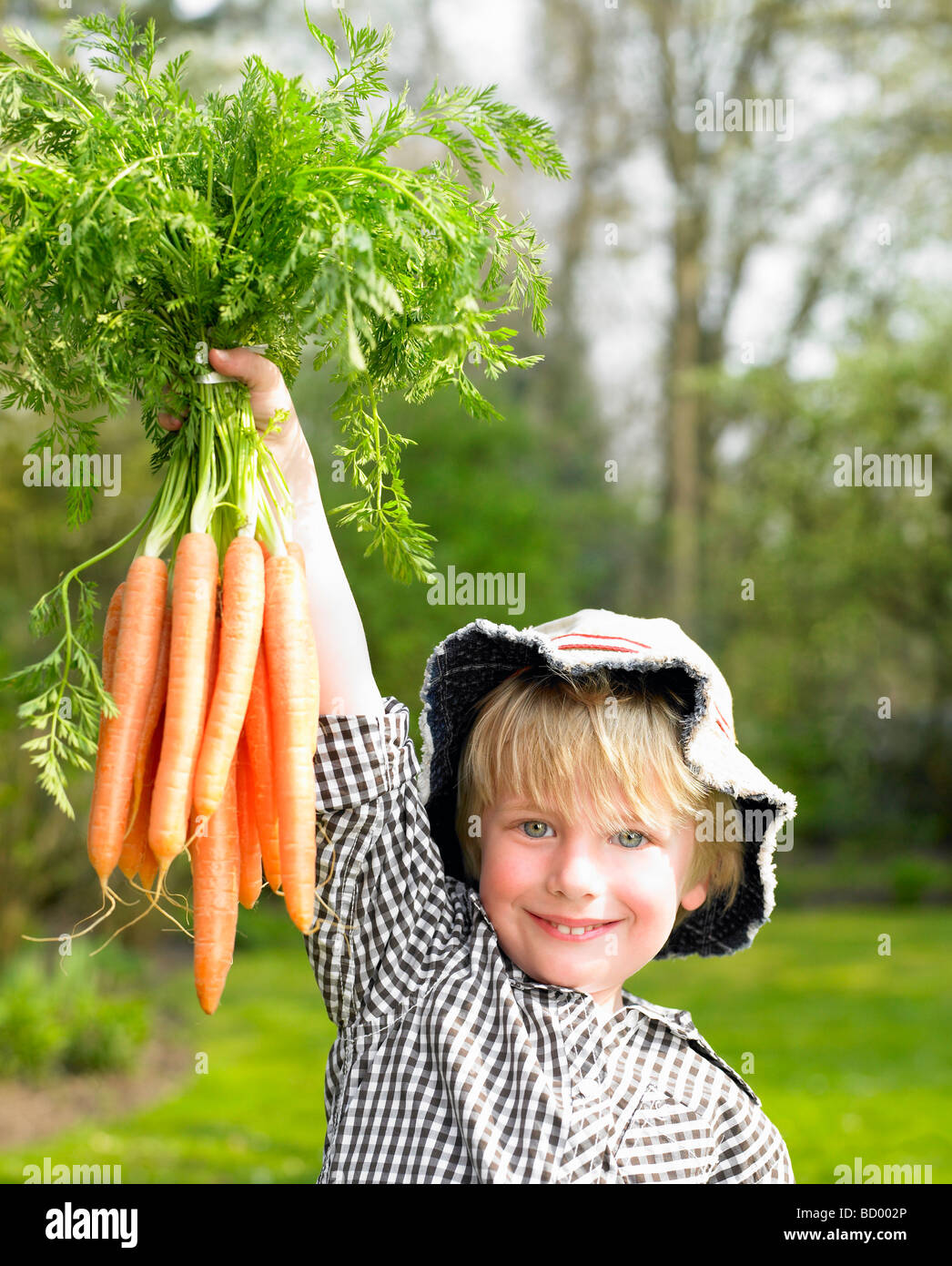 Ragazzo tenendo in mano un grappolo di carota Foto Stock