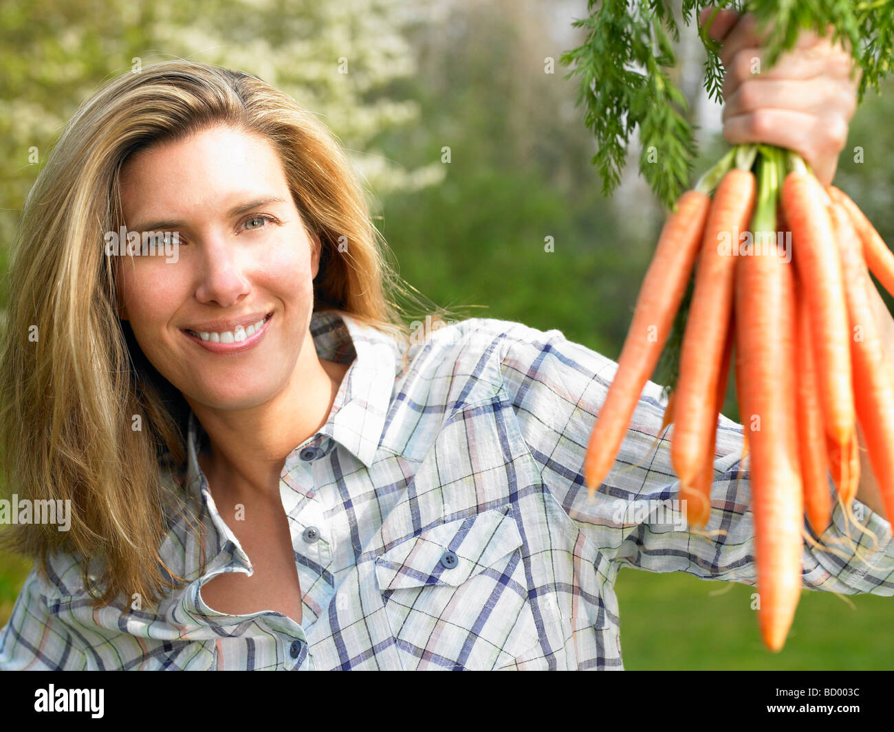Donna che mantiene un mazzetto di carota Foto Stock