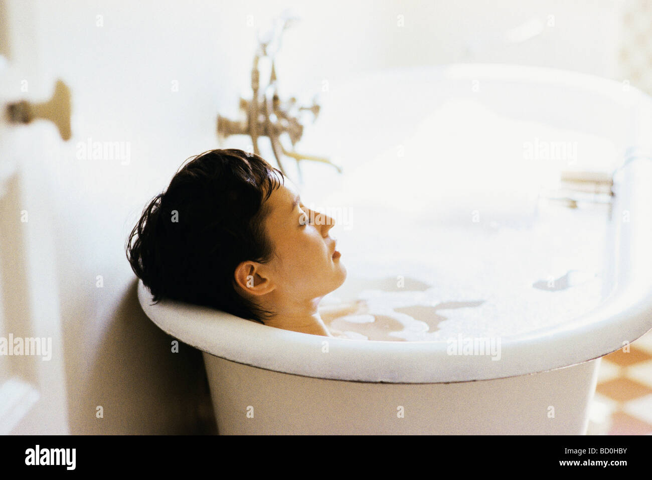 Donna immersione in bagno di bolle Foto Stock