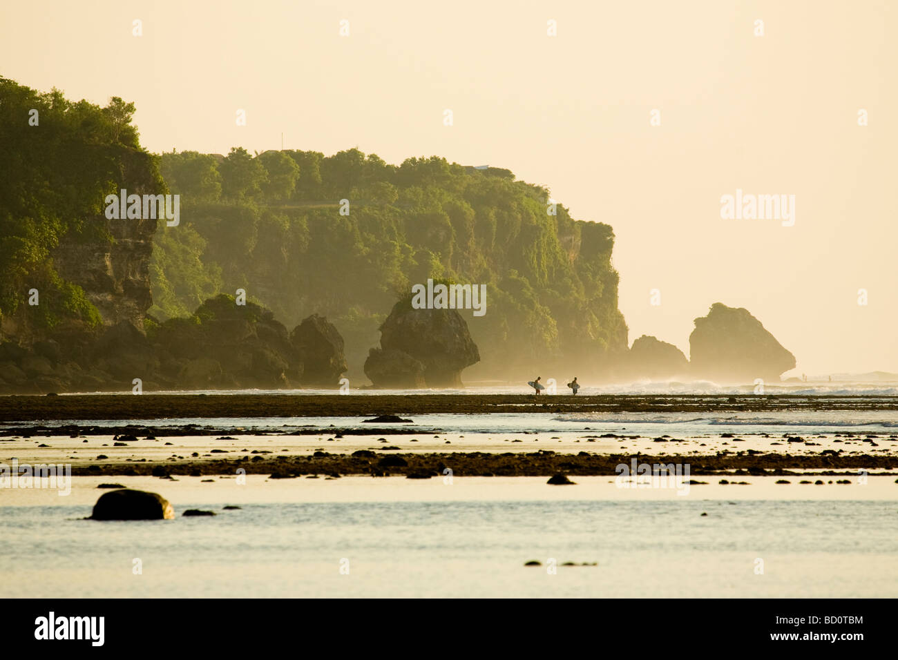 I surfisti attraversano il reef sulla spiaggia Bingin per una serata di surf a Impossibles, Bali, Indonesia Foto Stock