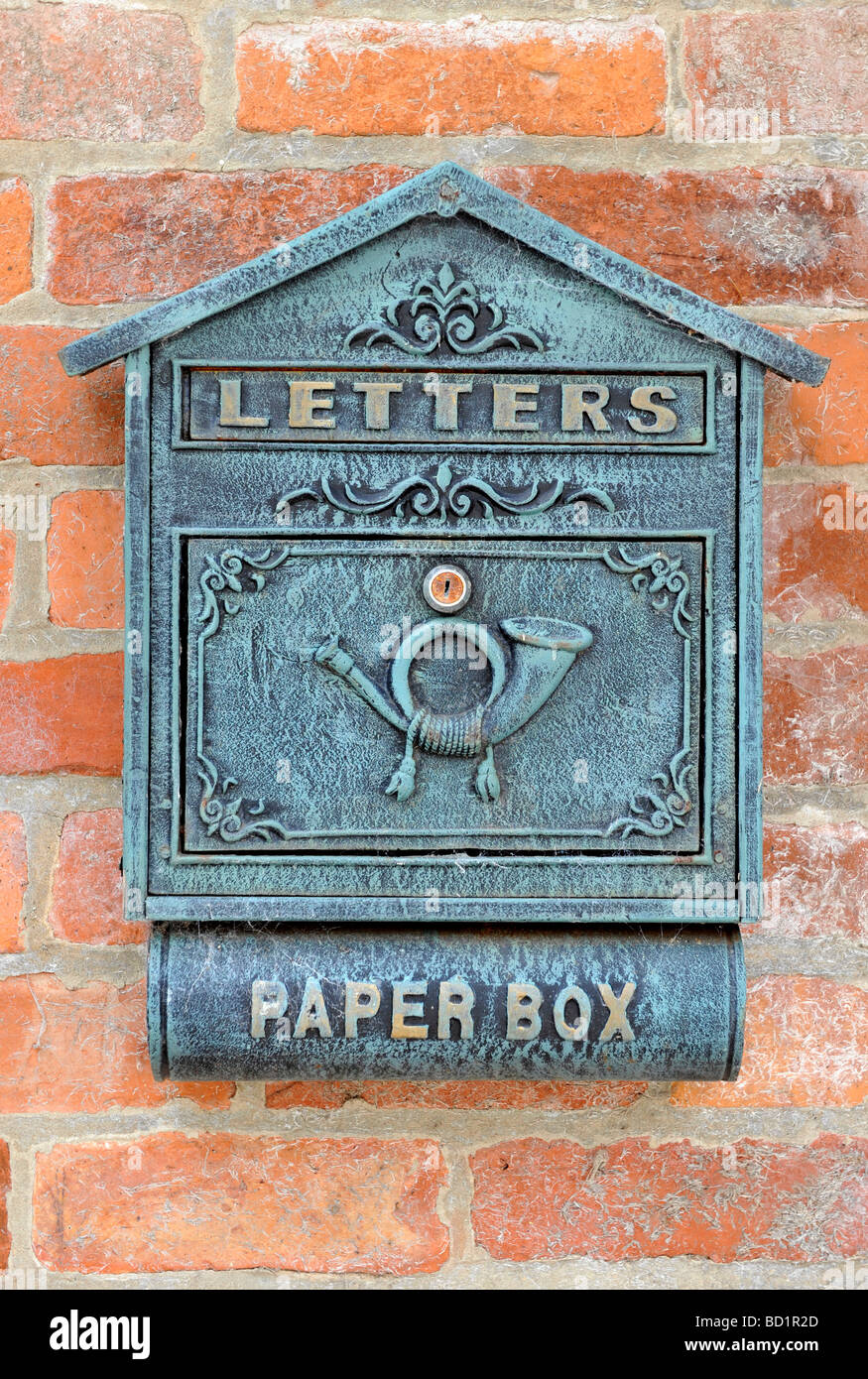 Una chiusura di un vecchio stile letter box carta contro una pietra rossa parete di mattoni Foto Stock