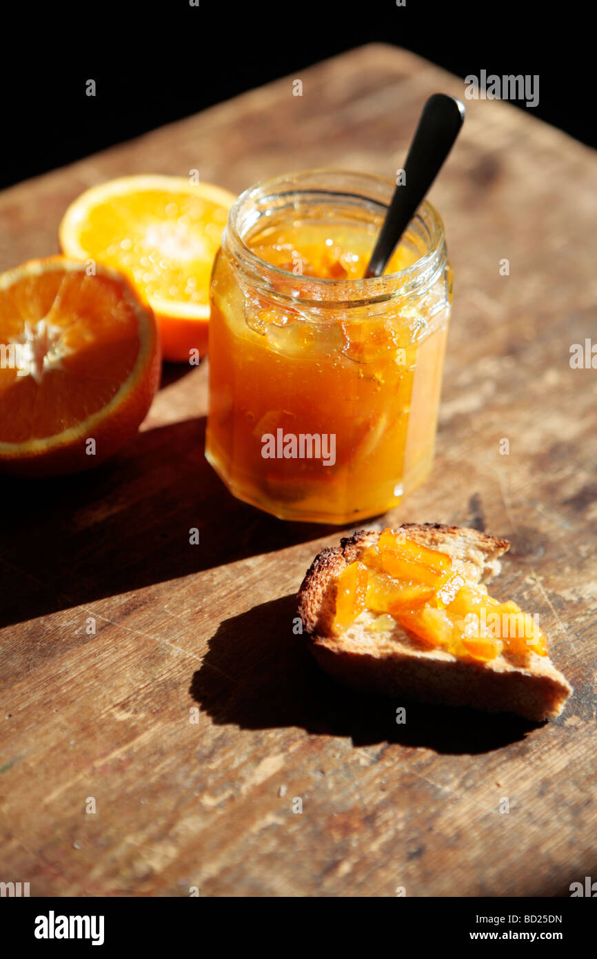 Un vasetto di marmellata di arance e le arance e marmellata sul pane tostato. Foto Stock