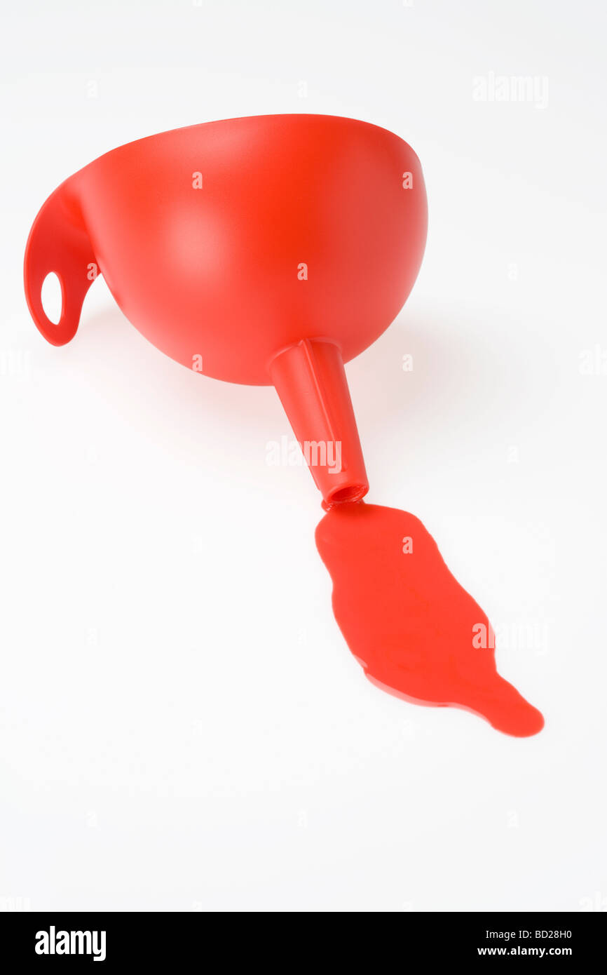 In rosso di un imbuto di plastica con un dribbling di rosso proveniente da esso Foto Stock