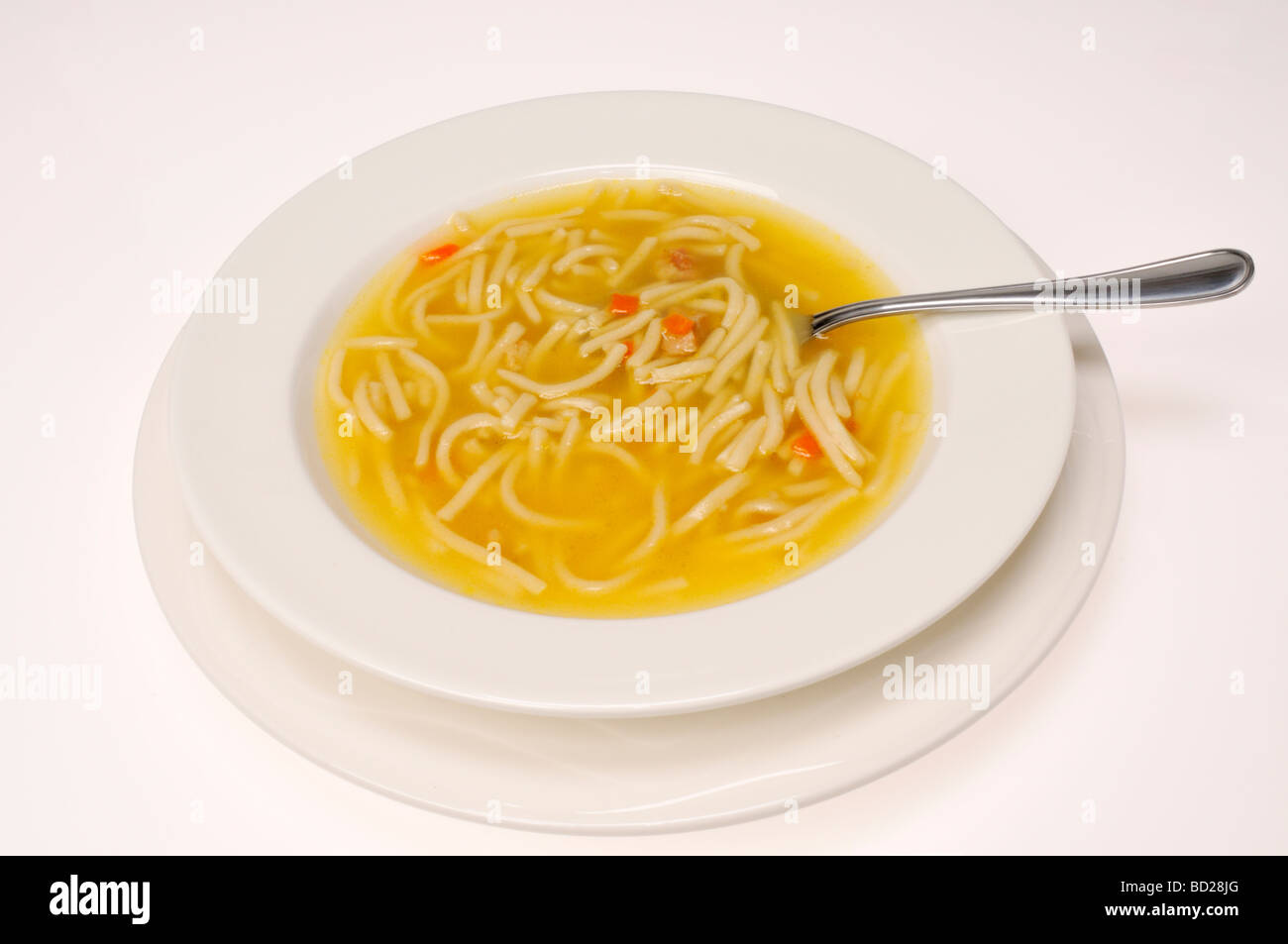 Ciotola di zuppa di noodle al pollo con cucchiaio su sfondo bianco. Foto Stock