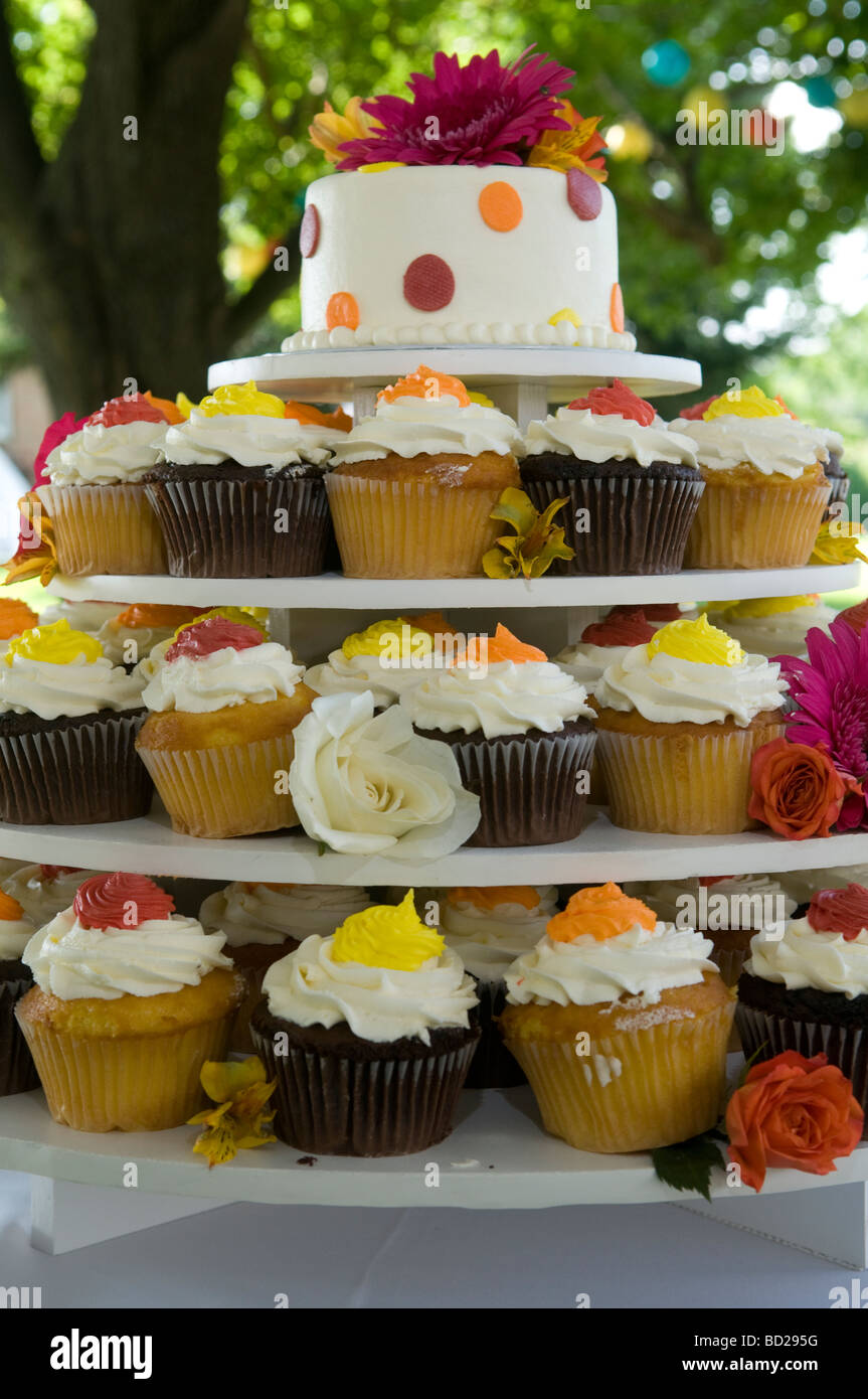 Quattro-tiered cupcake piatto con torta nuziale top decorato con fiori di seta. Foto Stock