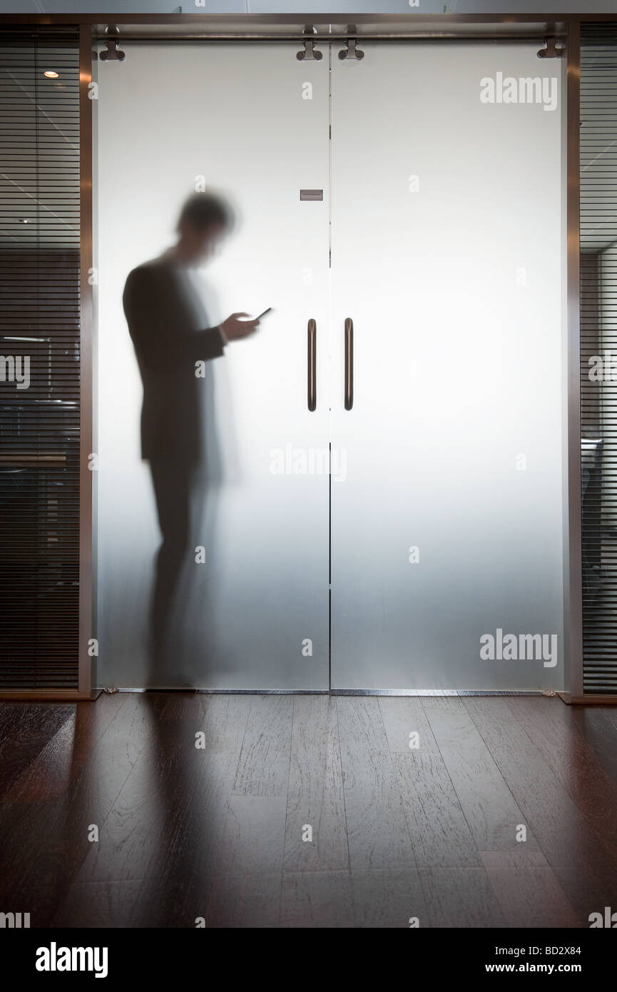 Imprenditore tenendo aperte le porte in vetro Foto Stock