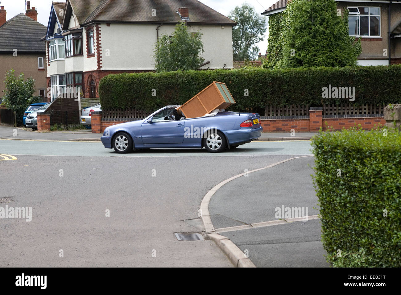 Una vettura convertibile portando un grande pezzo di arredamento su una strada del Regno Unito Foto Stock