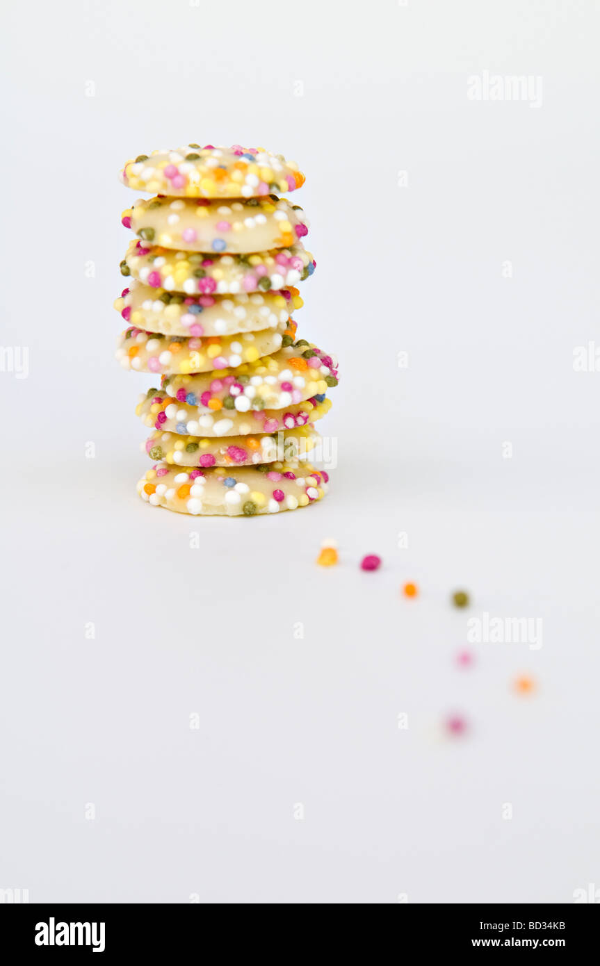 Ancora vita artistica di colpo il cioccolato bianco dolci pulsante coperto in spruzza prese contro uno sfondo bianco Foto Stock