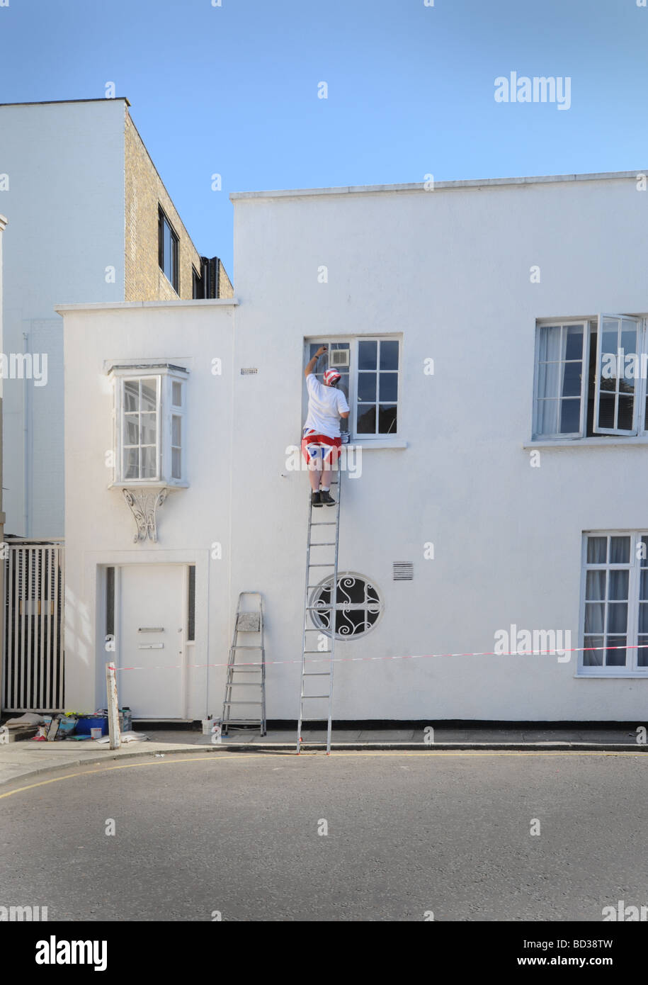 Casa pittore lavorando su una scala su una strada appena fuori la Kings Road, il Chelsea Londra Foto Stock