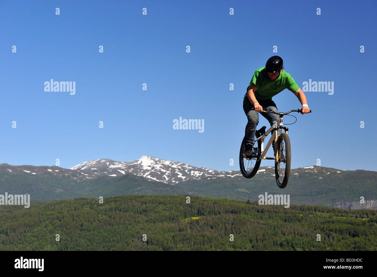 BMX rider volare in aria con la foresta e la montagna in background Foto Stock