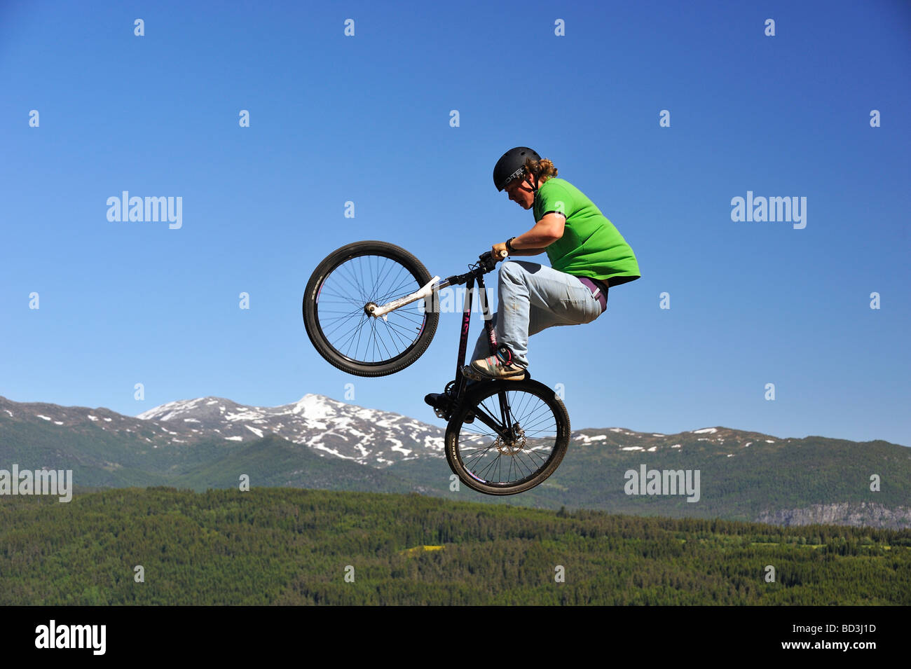 BMX rider volare in aria con la foresta e la montagna in background Foto Stock