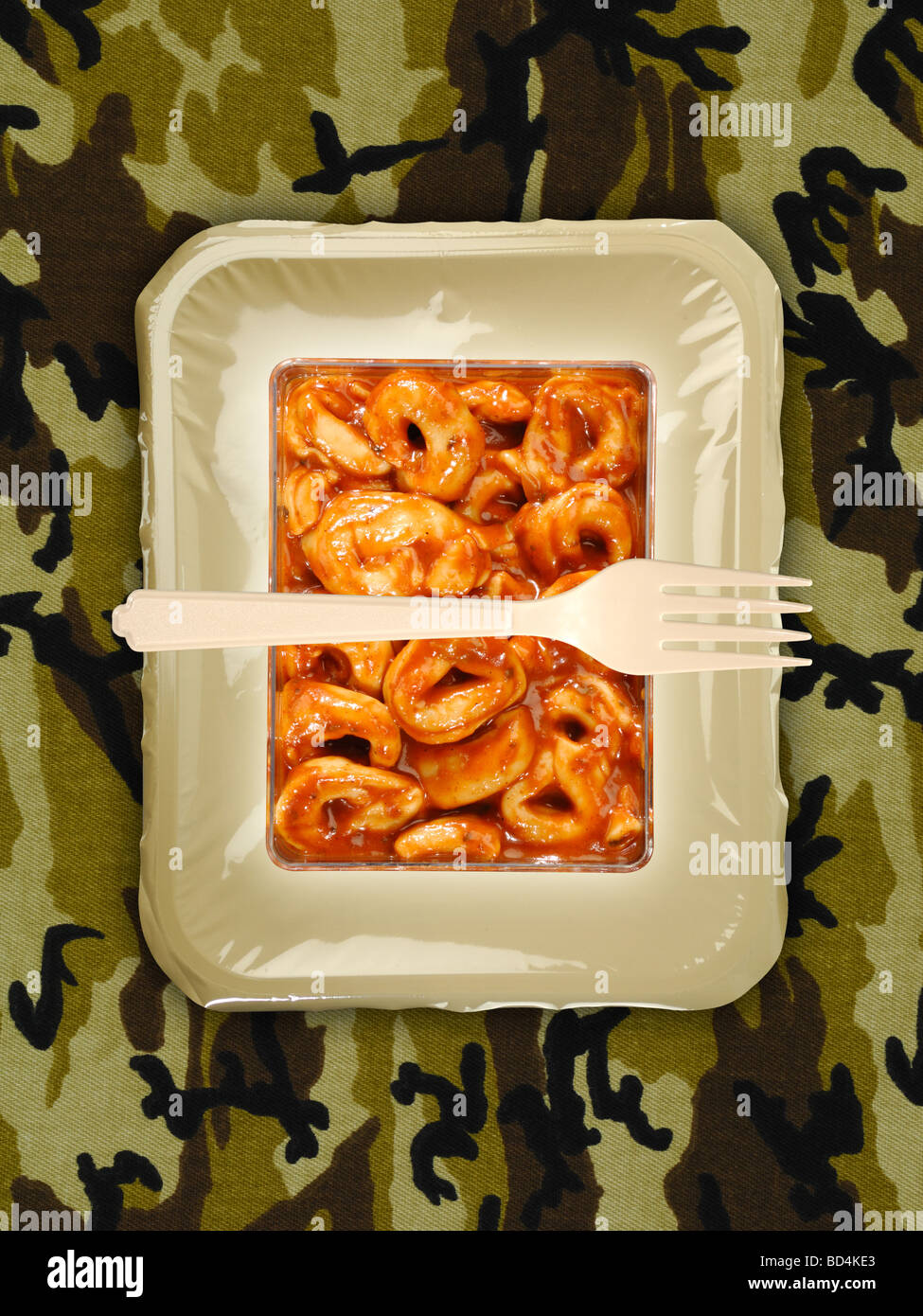 Un militare di razione di cibo pacchetto con una forcella su uno sfondo di tan camouflage, pasta al formaggio tortellini Foto Stock