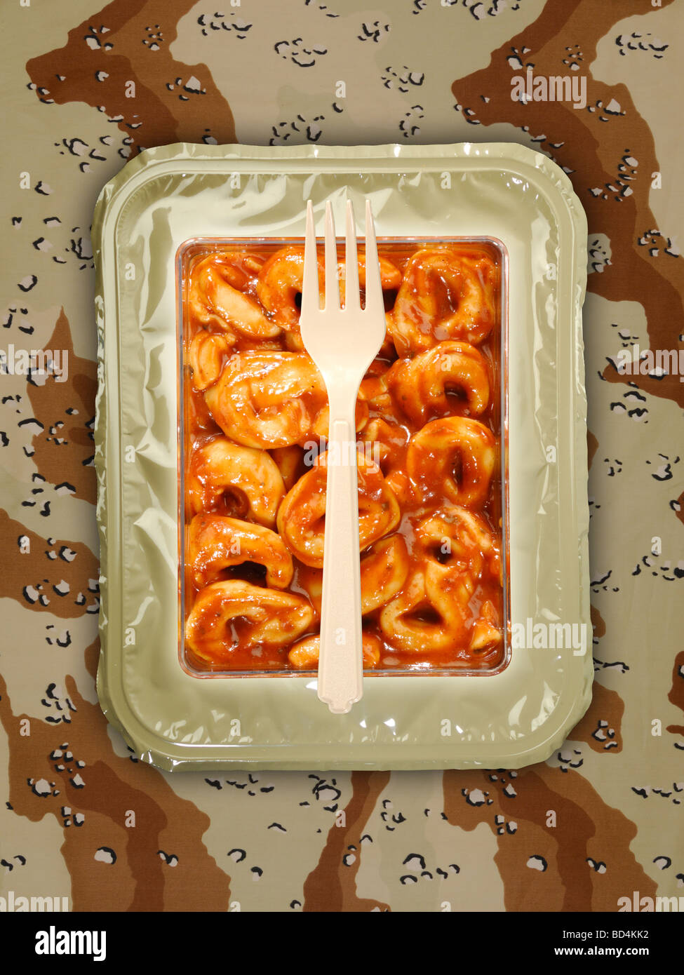 Un militare di razione di cibo pacchetto con una forcella su uno sfondo di tan camouflage, pasta al formaggio tortellini Foto Stock