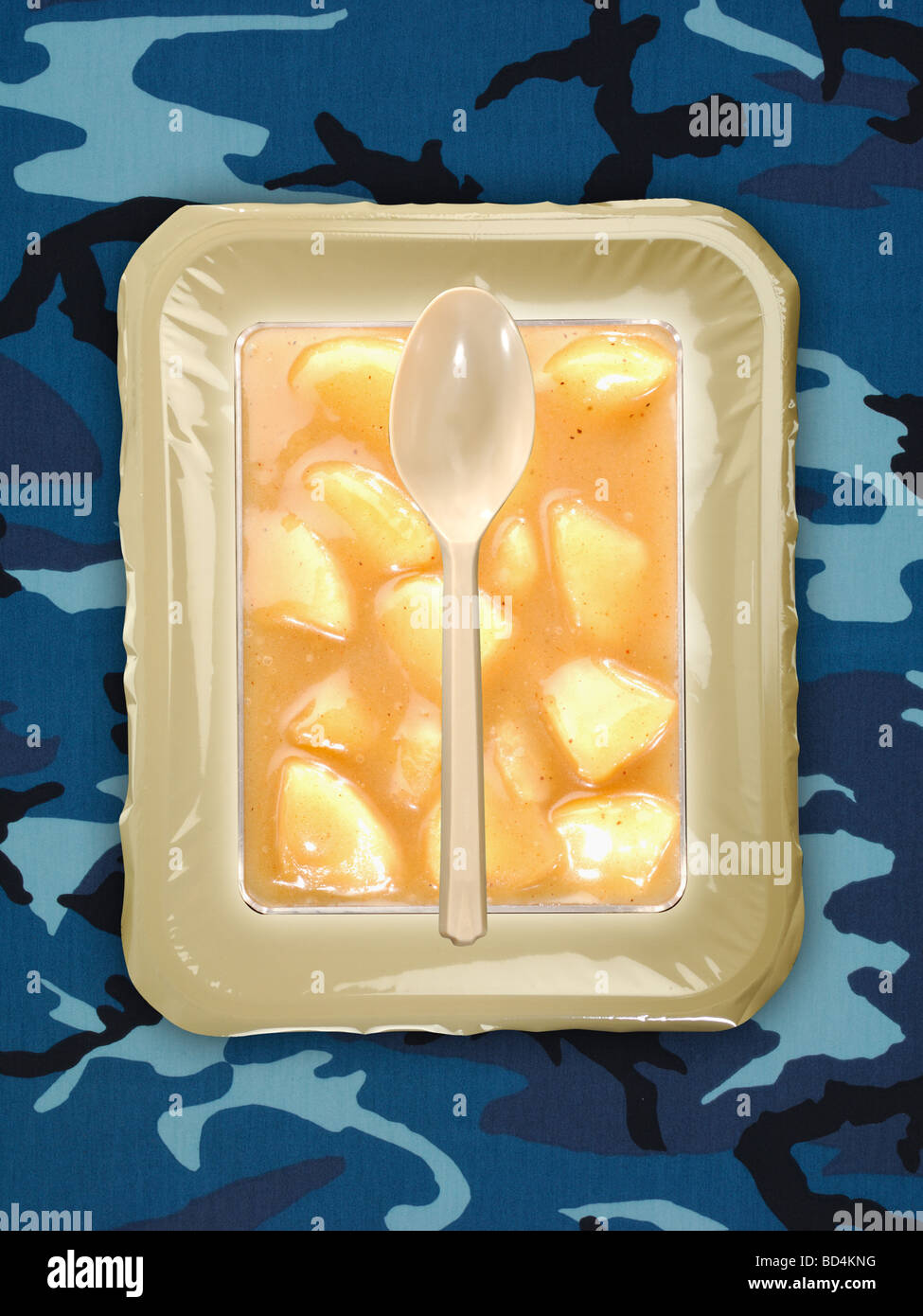 Un militare di razione di cibo pacchetto con un cucchiaio su uno sfondo di colore blu camouflage, pesche tagliate a fette Foto Stock