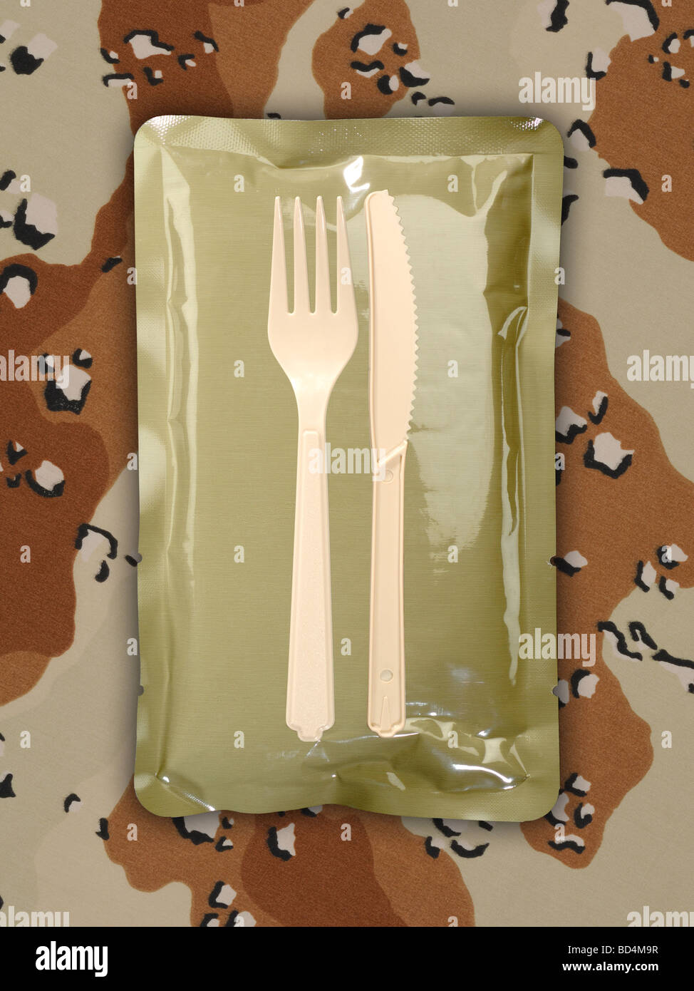 Militare una razione di cibo pacchetto con stoviglie su uno sfondo di tan camouflage Foto Stock