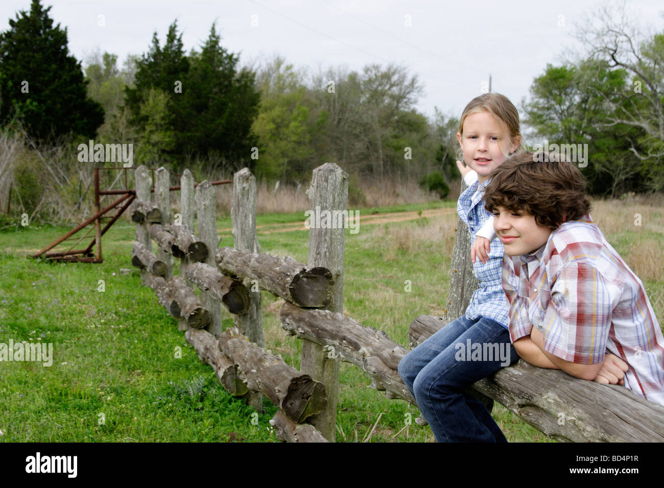 Fratello e Sorella di appendere fuori da un recinto nel paese Foto Stock