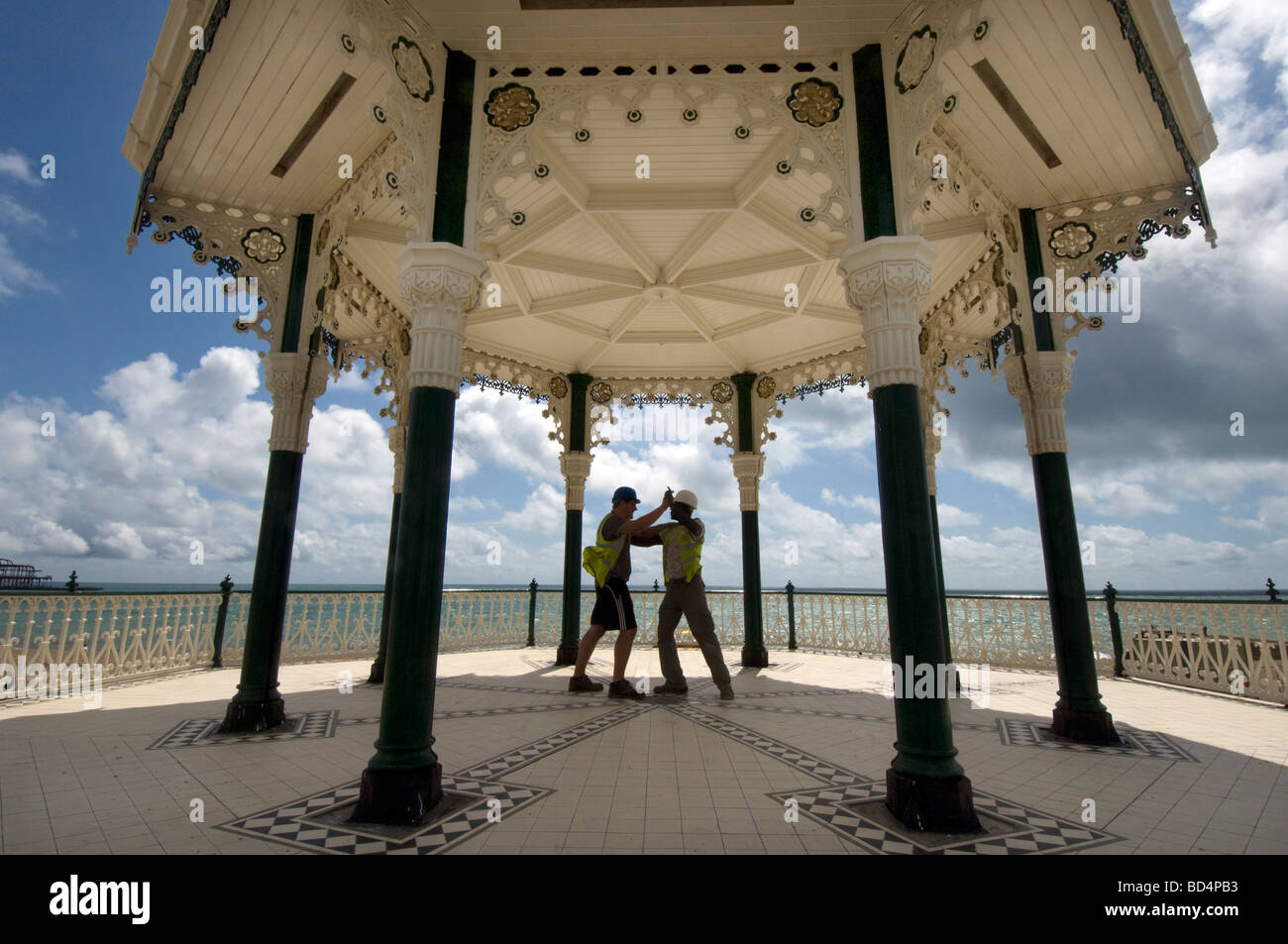 Due burly costruttori in elmetti e giubbotti di sicurezza danza per celebrare il milione libbre il rinnovo di Brighton bandstand. Foto Stock