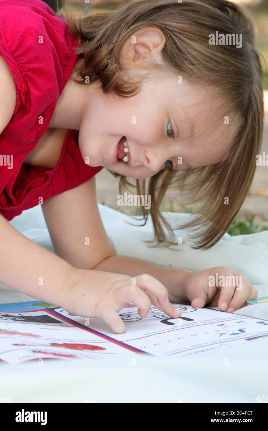 Giovane ragazza divertirsi giocando giochi didattici da un libro Foto Stock