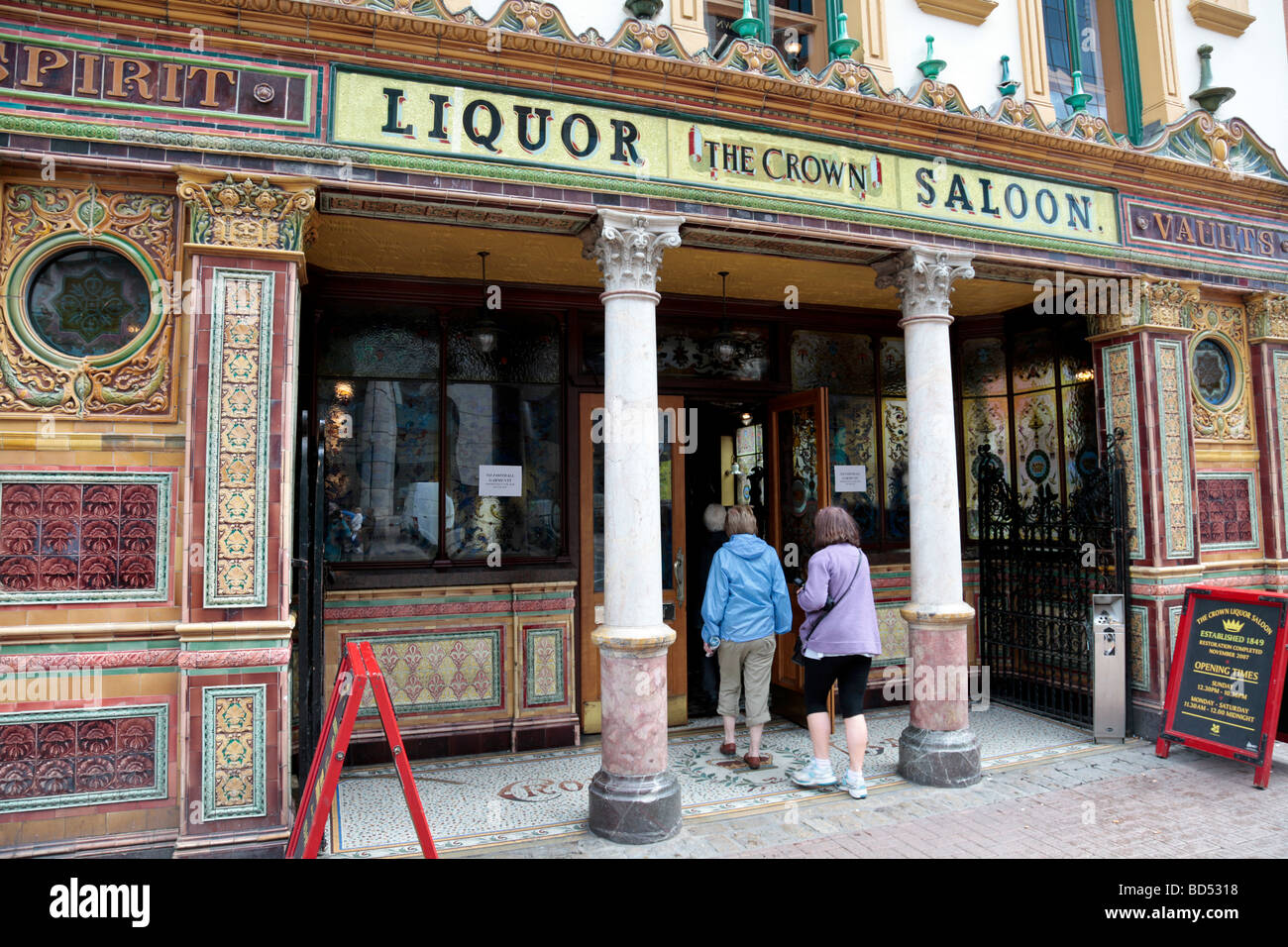 Due persone di entrare nella famosa Crown Liquor Saloon di Belfast, che è di proprietà ed è stato restaurato dalla National Trust ed è un grado un edificio elencato. Foto Stock