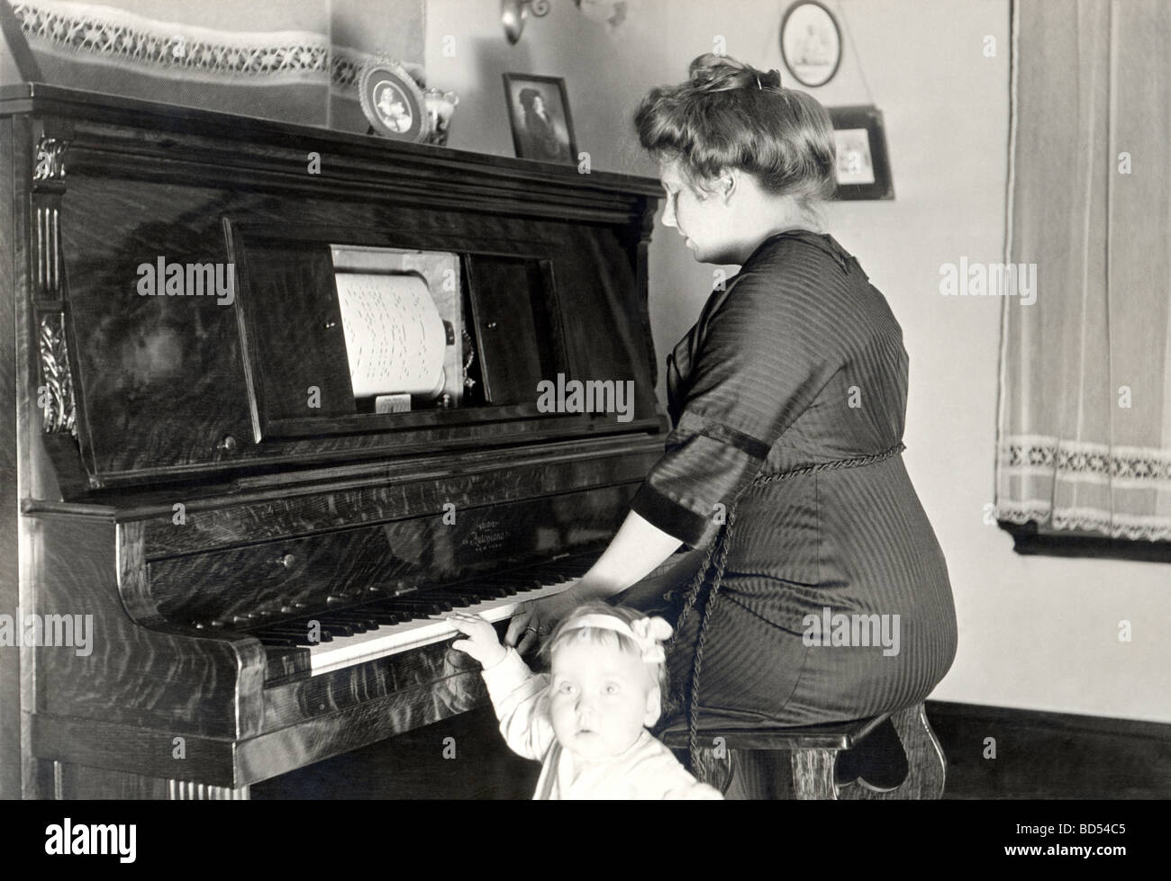 La madre a Player Piano con la figlia Foto Stock