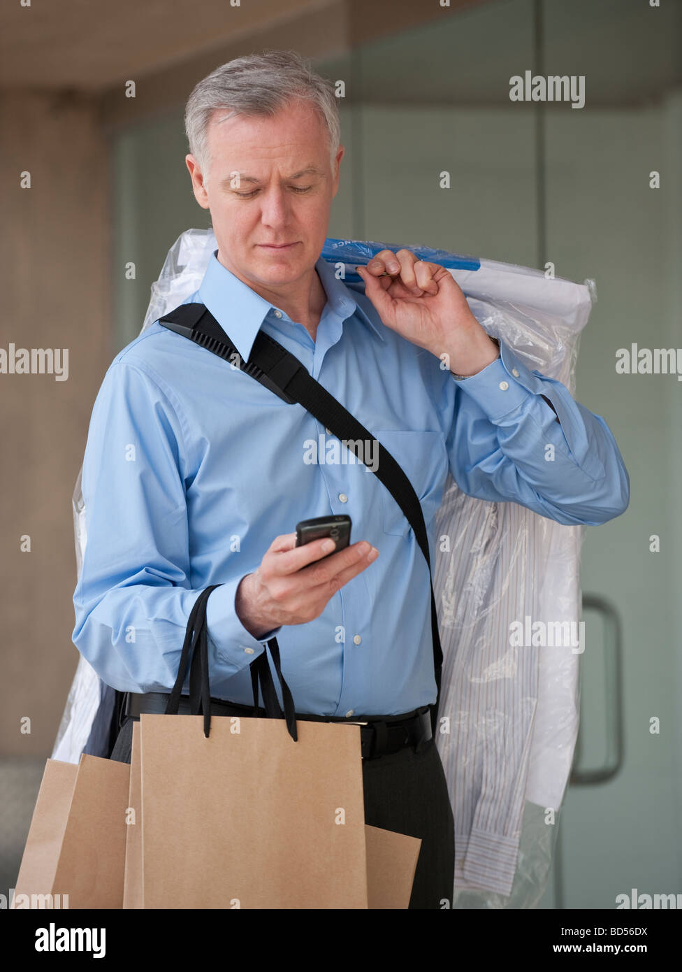 Un uomo con lavaggio a secco e di borse per lo shopping Foto Stock