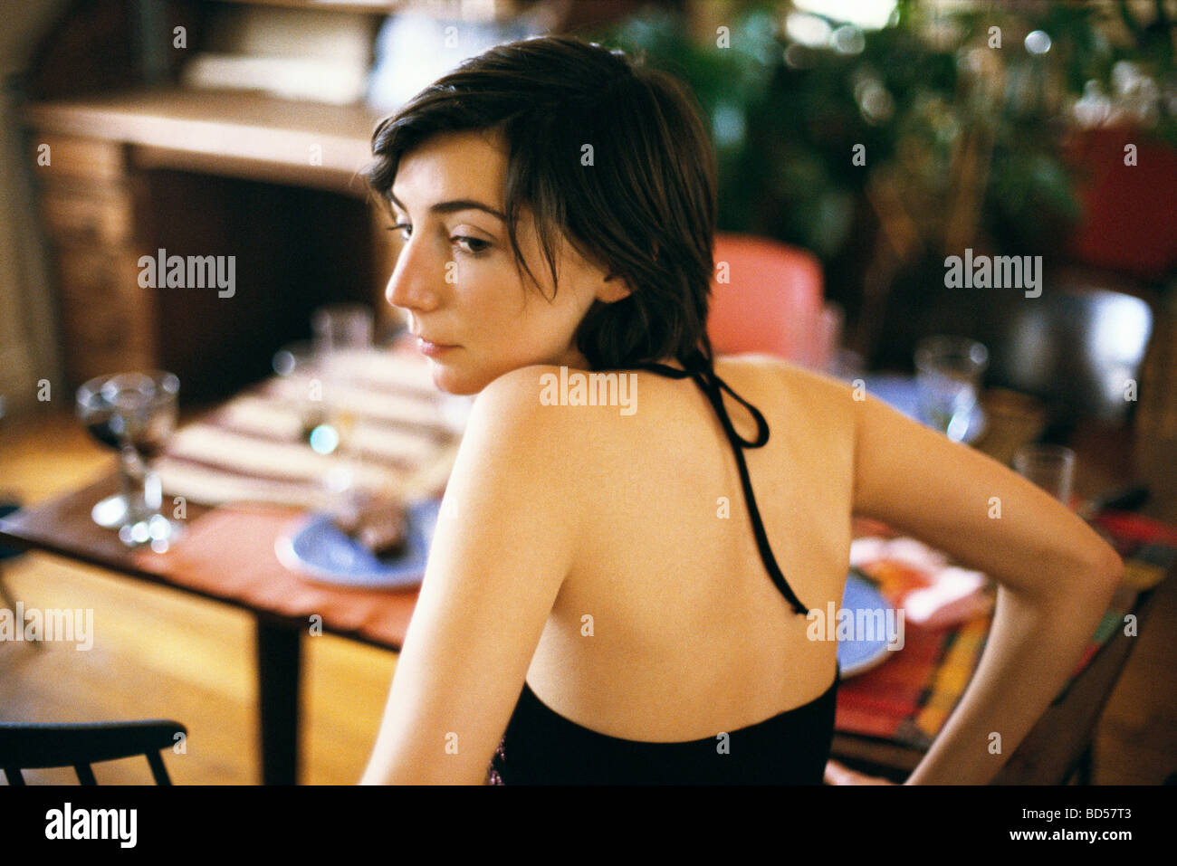 Donna che guarda oltre lo spallamento contemplatively guardando lontano, impostare la tabella in background Foto Stock