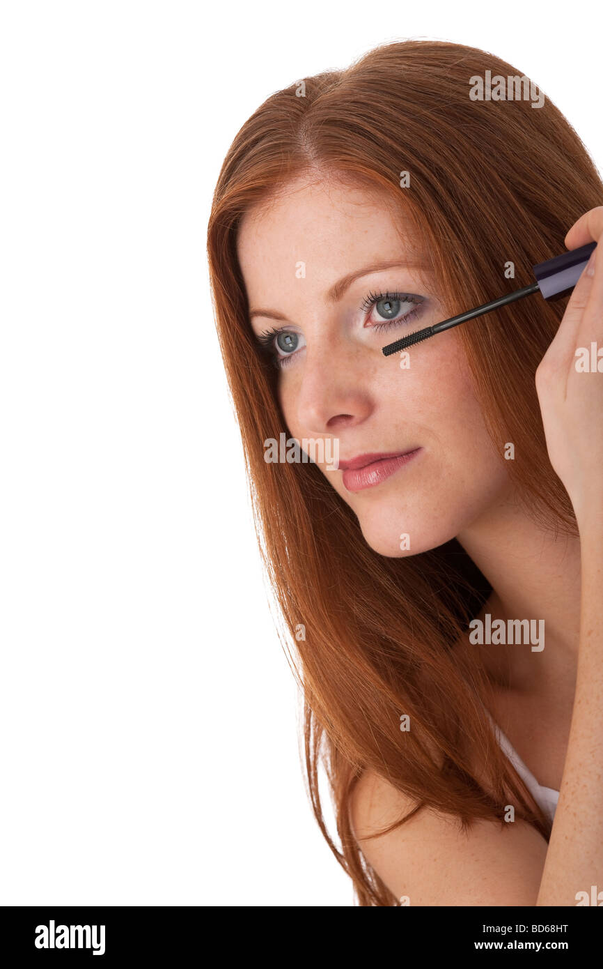 Cura del corpo - bella capelli rossi donna applicazione di mascara su sfondo bianco Foto Stock