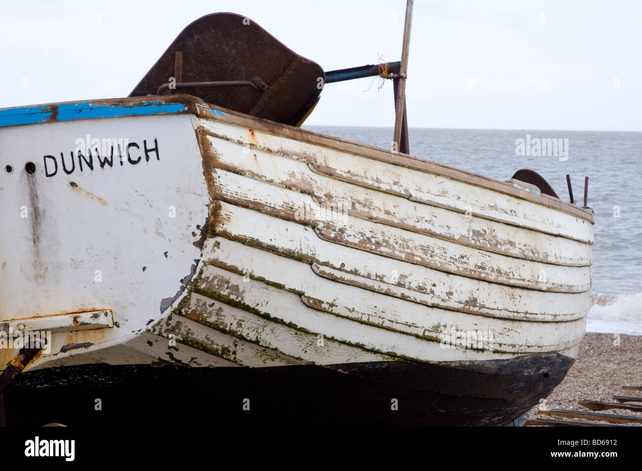 Un vecchio legno barca da pesca seduto sulla spiaggia di ciottoli a Dunwich, Suffolk, Inghilterra Foto Stock