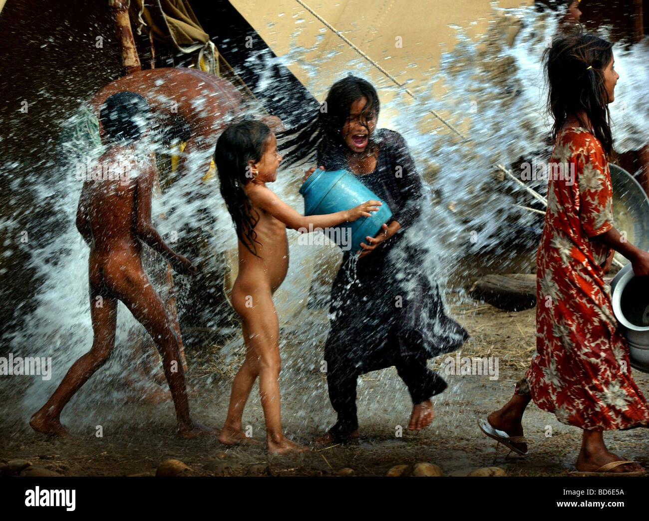 I bambini che sono stati costretti a migrare dalla loro casa a Pargwal India cool off come un carrello che spruzza acqua su di loro nei pressi di Ahknoor in Foto Stock