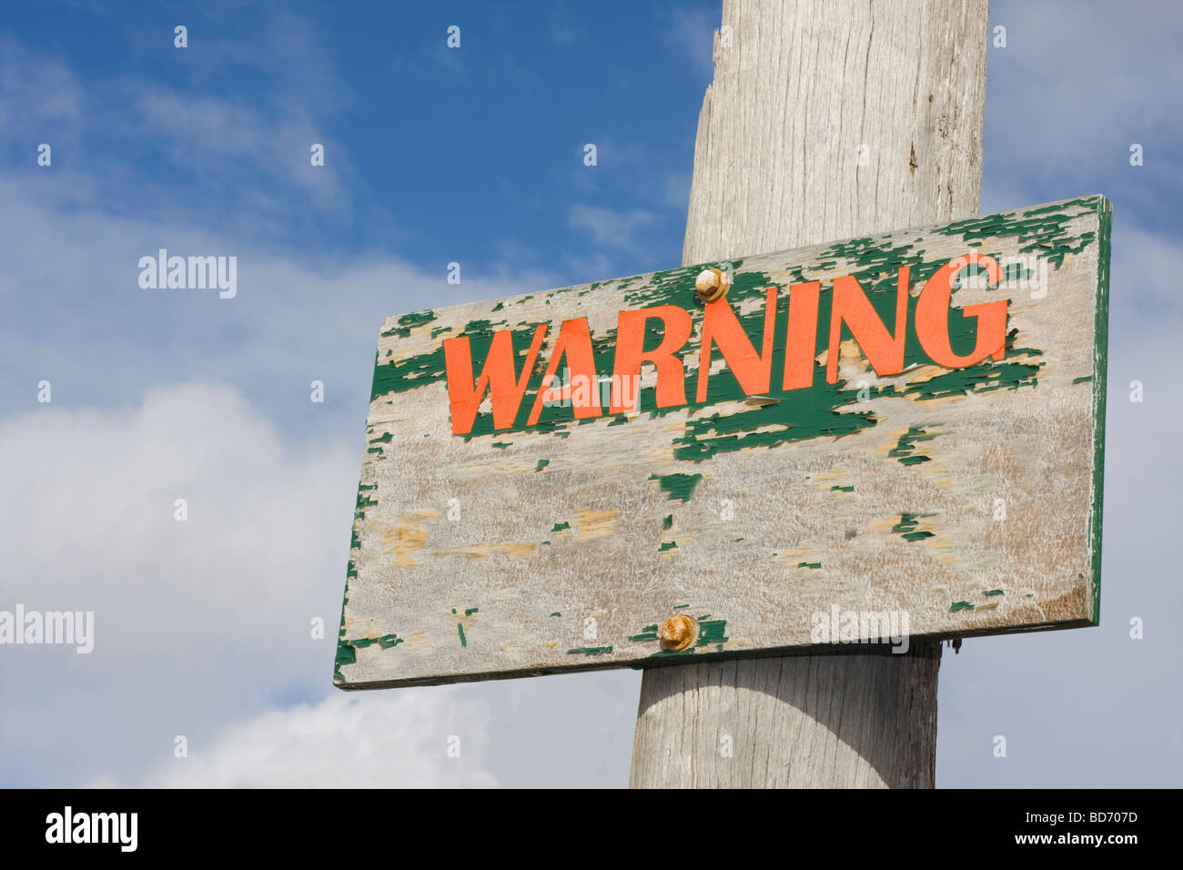 In legno antico segno di avvertimento con cielo blu e nuvole sullo sfondo Foto Stock
