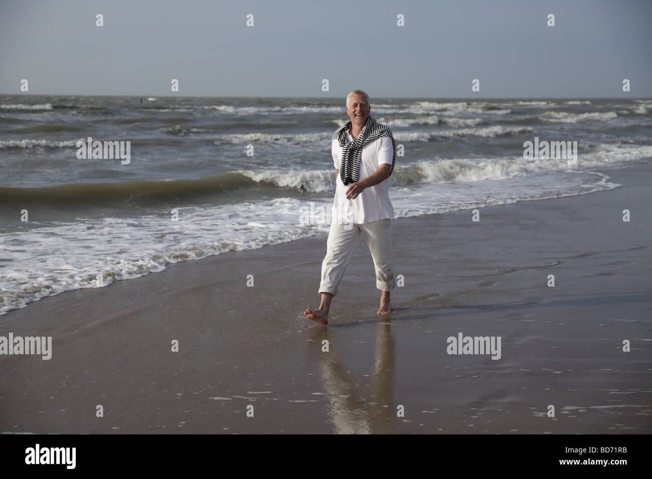 Voce maschile Best Ager di camminare sulla spiaggia del Mare del Nord a De Haan, Belgio, Europa Foto Stock