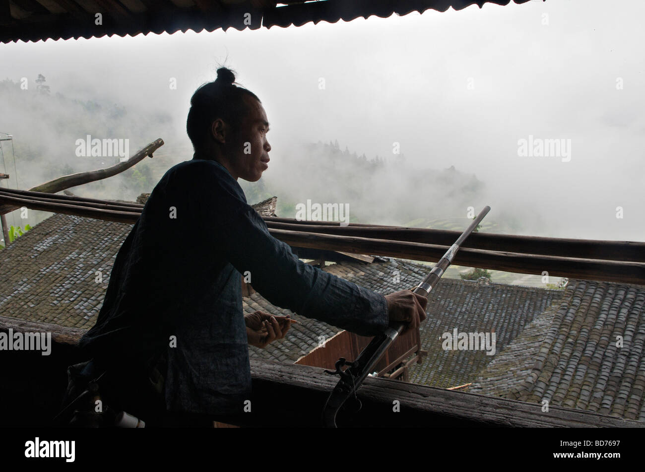 Basha Miao l uomo con la pistola affacciato sul villaggio di contea Congjiang Guizhou Cina Foto Stock