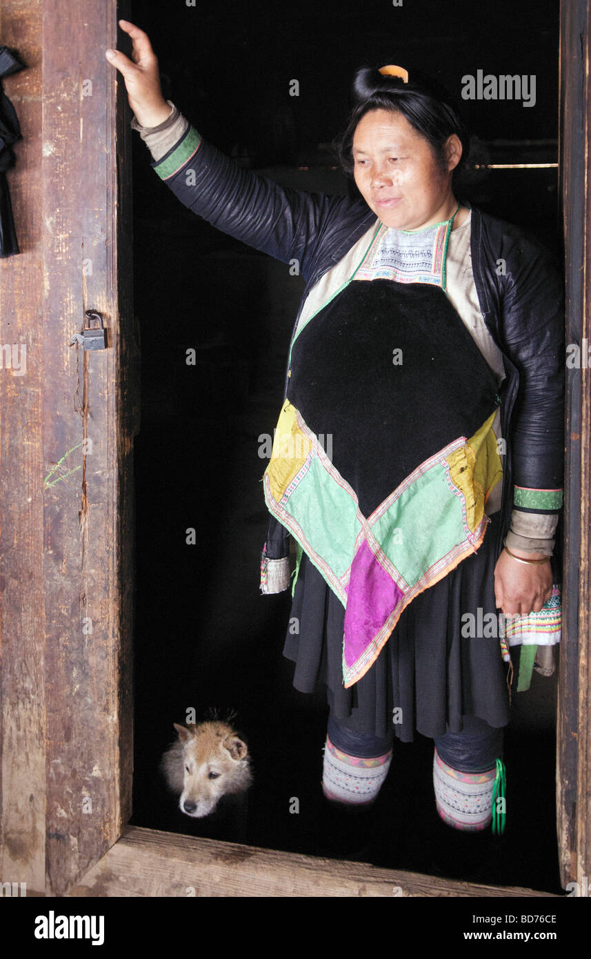 Interior Basha Miao donna con cane in porta Congjiang County Guizhou Cina Foto Stock