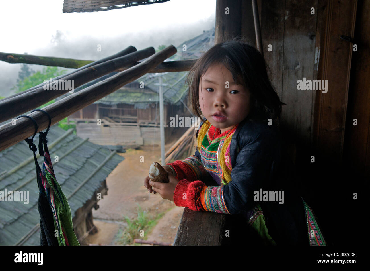 Piccolo Basha Miao ragazza nella veranda della casa di villaggio contea Congjiang Guizhou Cina Foto Stock