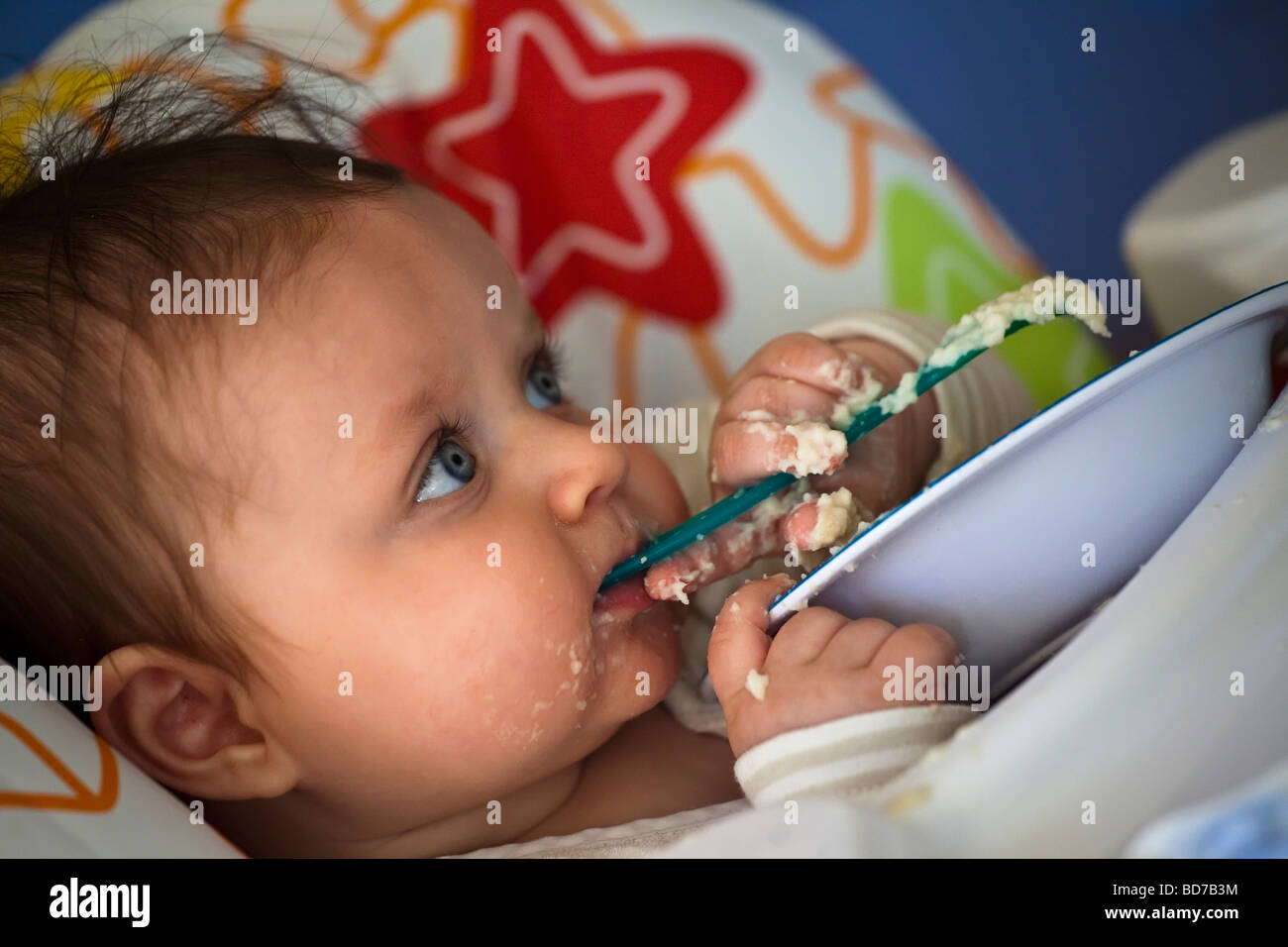 I giovani baby sotto i sei mesi di età cucchiaio alimentazione e facendo un pasticcio Foto Stock