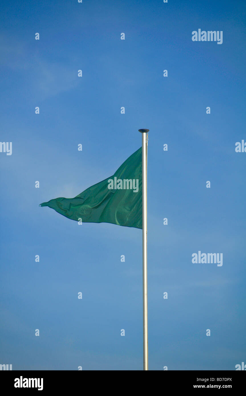 Bandiera verde battenti nel vento nel cielo blu Foto Stock