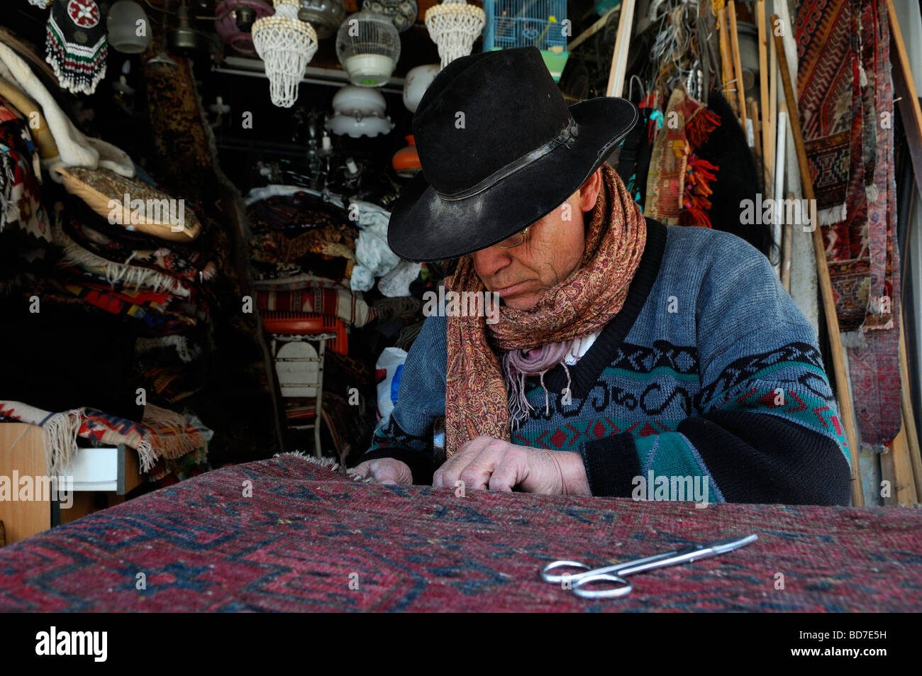 Un uomo che ripara un tappeto in un negozio nella Vecchia Jaffa il mercato delle pulci di Israele Foto Stock