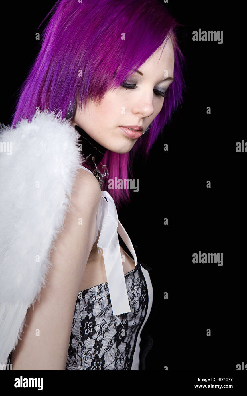 Colpo di alternativa viola ragazza dai capelli con ali d'Angelo contro uno sfondo nero Foto Stock