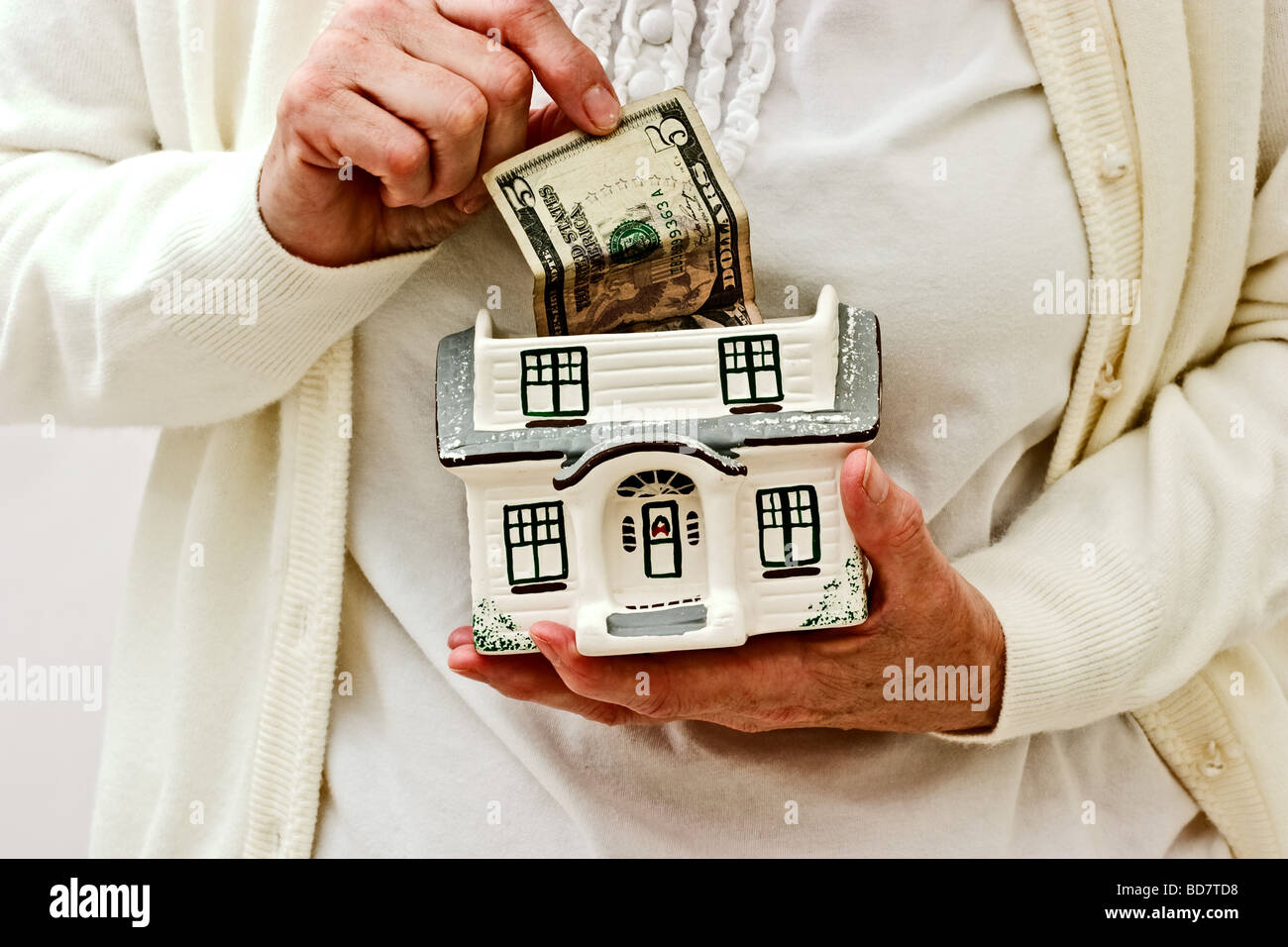 Donna tirando i soldi della parte superiore di una piccola casa in ceramica Foto Stock