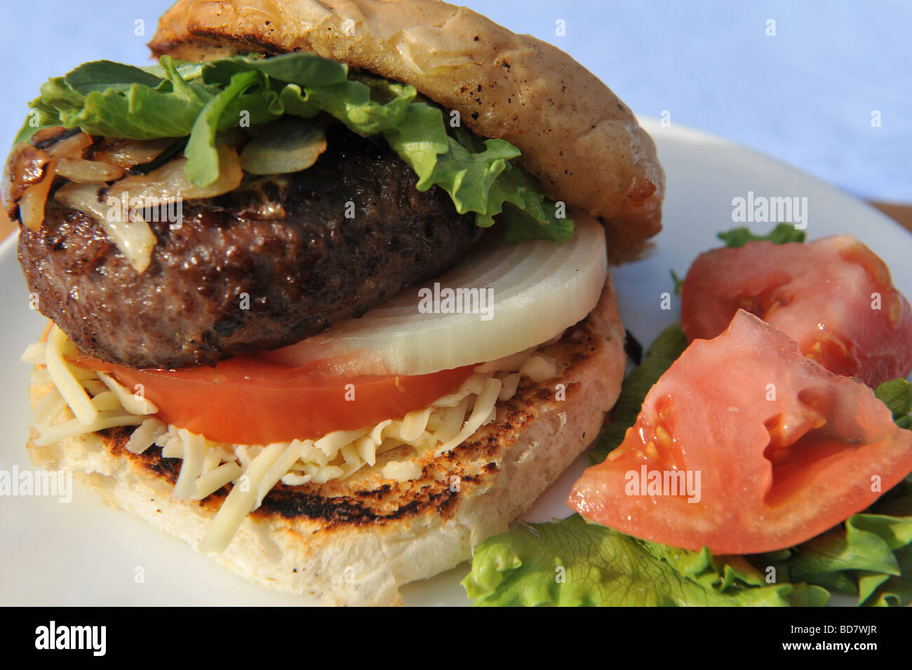 Hamburger di manzo in un panino con il formaggio cipolla ed insalata Foto Stock
