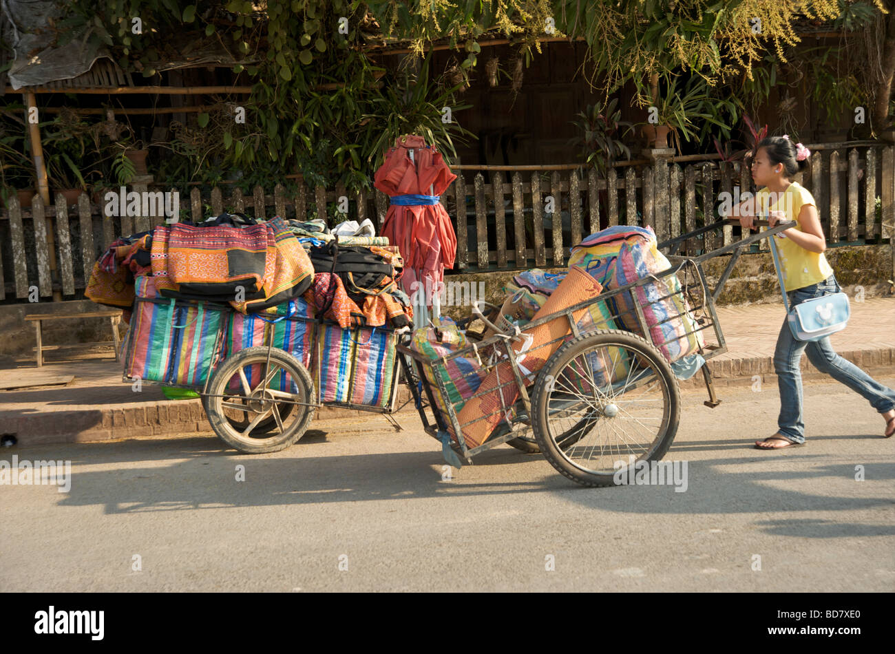 Un portone spinge il suo carrello per mettere la sua stalla souvenir nel mercato notturno di Luang Prabang Laos Foto Stock