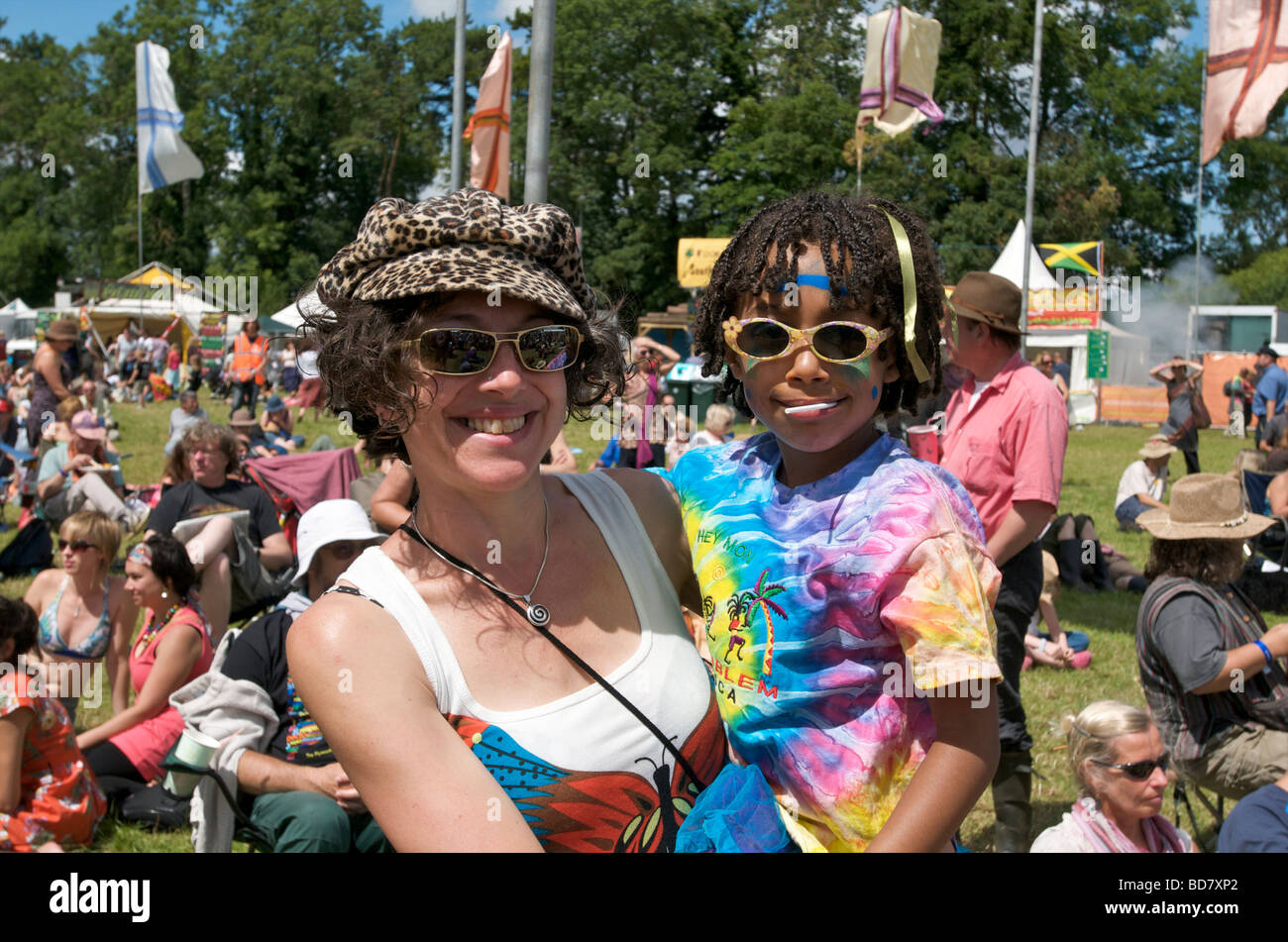 Un sorridenti mamma indossando occhiali da sole mentre tiene il suo bambino davanti a una folla di persone al festival Womad Foto Stock