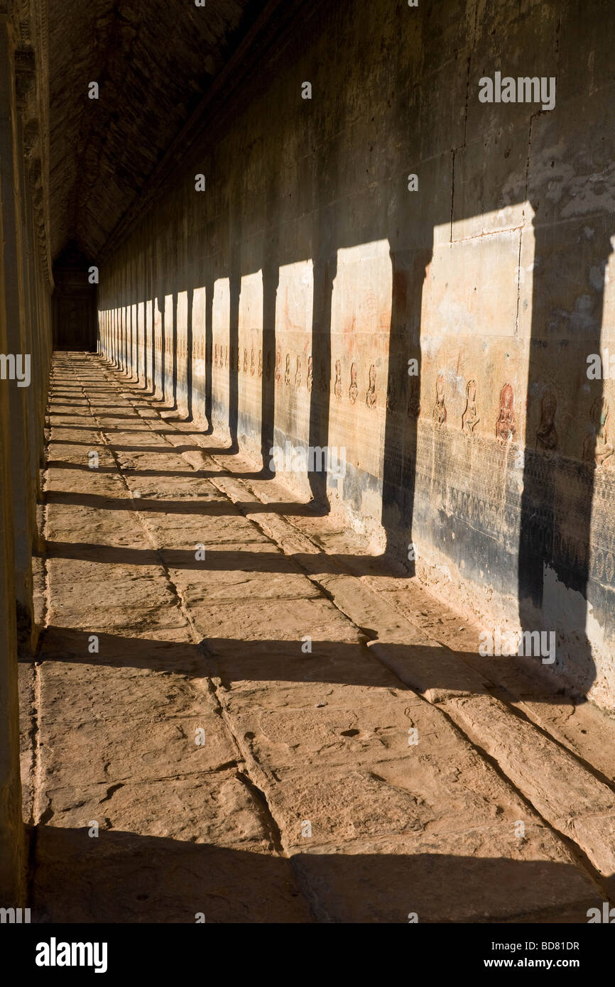 Luce della Sera getta ombre forte da montanti verticali in gallerie esterna di Angkor Wat Foto Stock