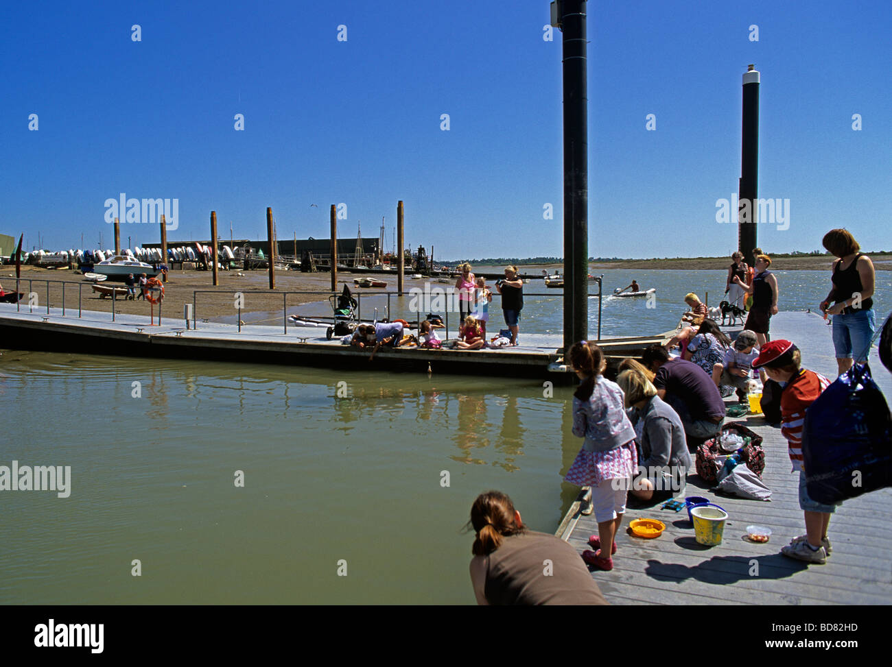 Bambini e genitori pescato granchi dal dock comunale a Brightlingsea sul fiume Colne in Essex Foto Stock