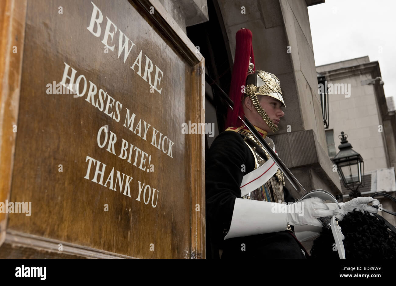 Ceremonially uniformata Horse Guard sul dazio ad Admiralty Arch, Whitehall, a Londra con il cartello di avviso per i turisti Foto Stock