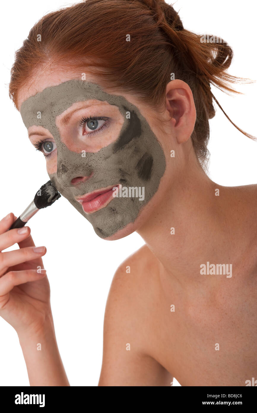 Cura del corpo - una giovane donna con maschera di fango su sfondo bianco Foto Stock