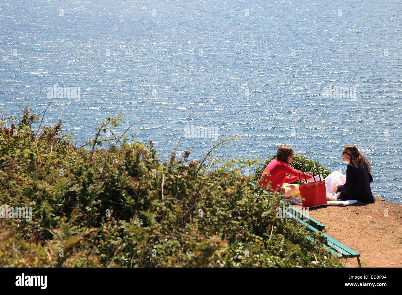 Due donne mangiare sul bordo della scogliera con una vista sul mare nei pressi di Jerbourg Point a Guernsey Isole del Canale Foto Stock