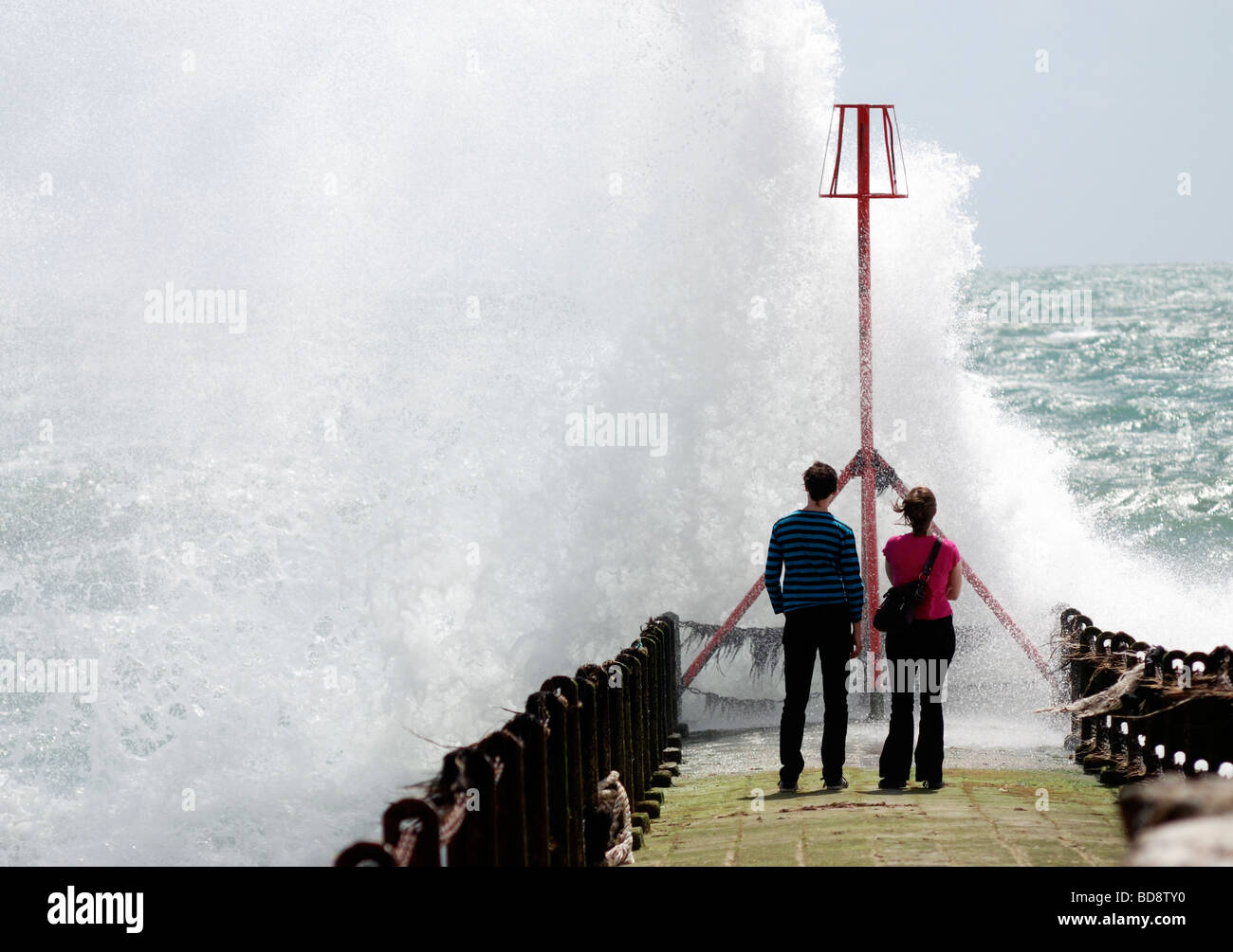 Un paio di stand su un molo e guardare le onde di un mare agitato break Foto Stock