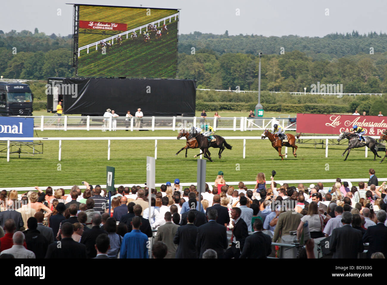 Frequentatori di gara guarda alla fine di una gara in diretta e su un grande schermo a Ascot Race Course, vicino a Windsor, Berkshire, Regno Unito. Foto Stock