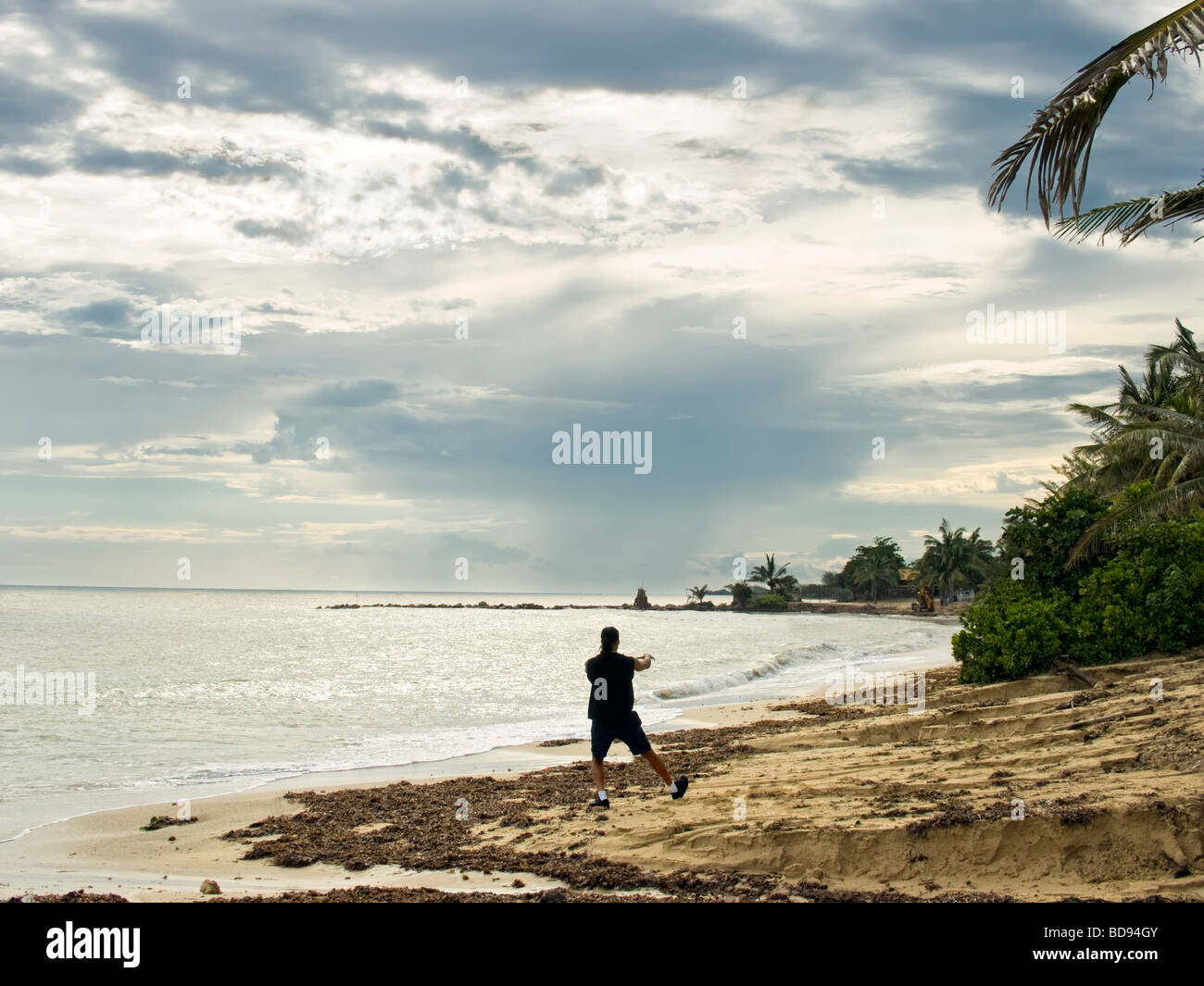 Un uomo solitario practice tai chi su una spiaggia dopo una tempesta tropicale Foto Stock